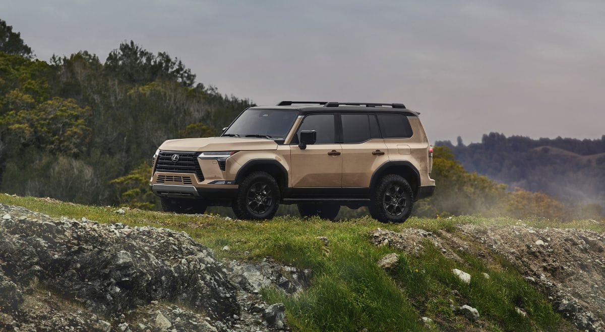 2025 Lexus GX550 Overtrail SUV with 33-inch all-terrain tires, off-road bumpers, and rugged Overtrail design package parked on rocky desert terrain.