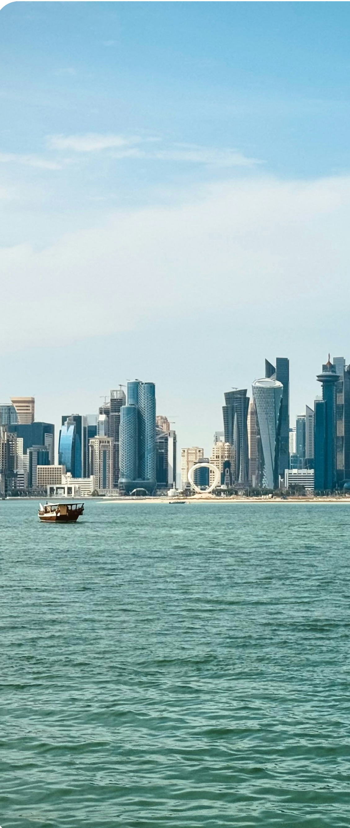 Doha West Bay skyline by day with a traditional dhow boat, Qatar