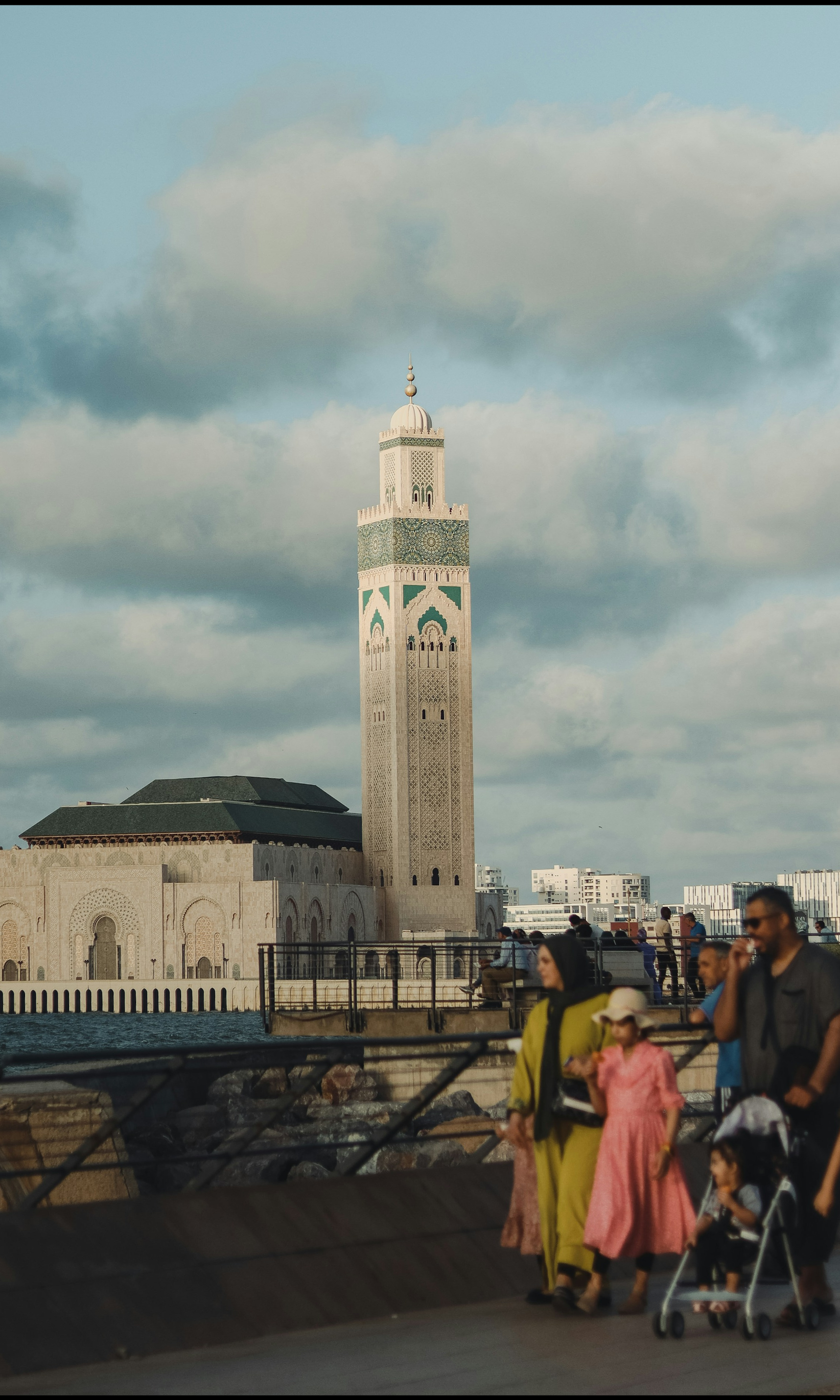 Families walking the Casablanca corniche near Hassan II Mosque, everyday city life.