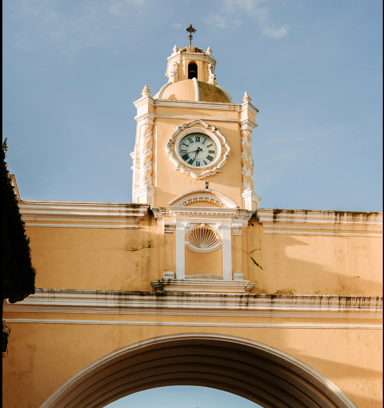 Santa Catalina Arch clock tower in Antigua Guatemala, with a volcano visible through the arch