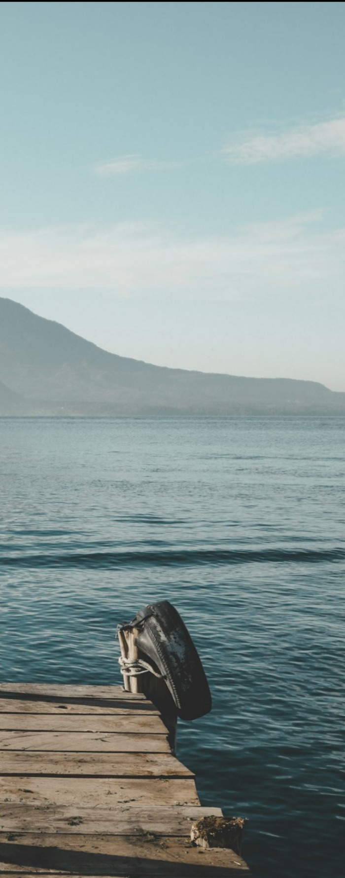 A wooden dock on Lake Atitlan with volcanoes in the distance, Guatemala