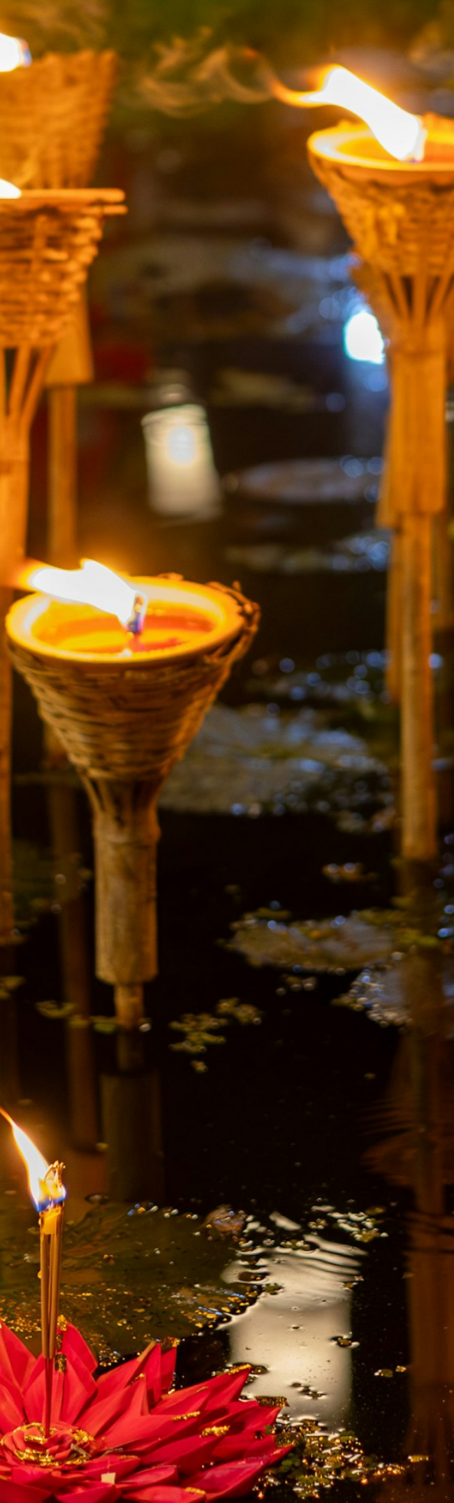 Floating krathong candles and torches on the water during Loi Krathong in Thailand