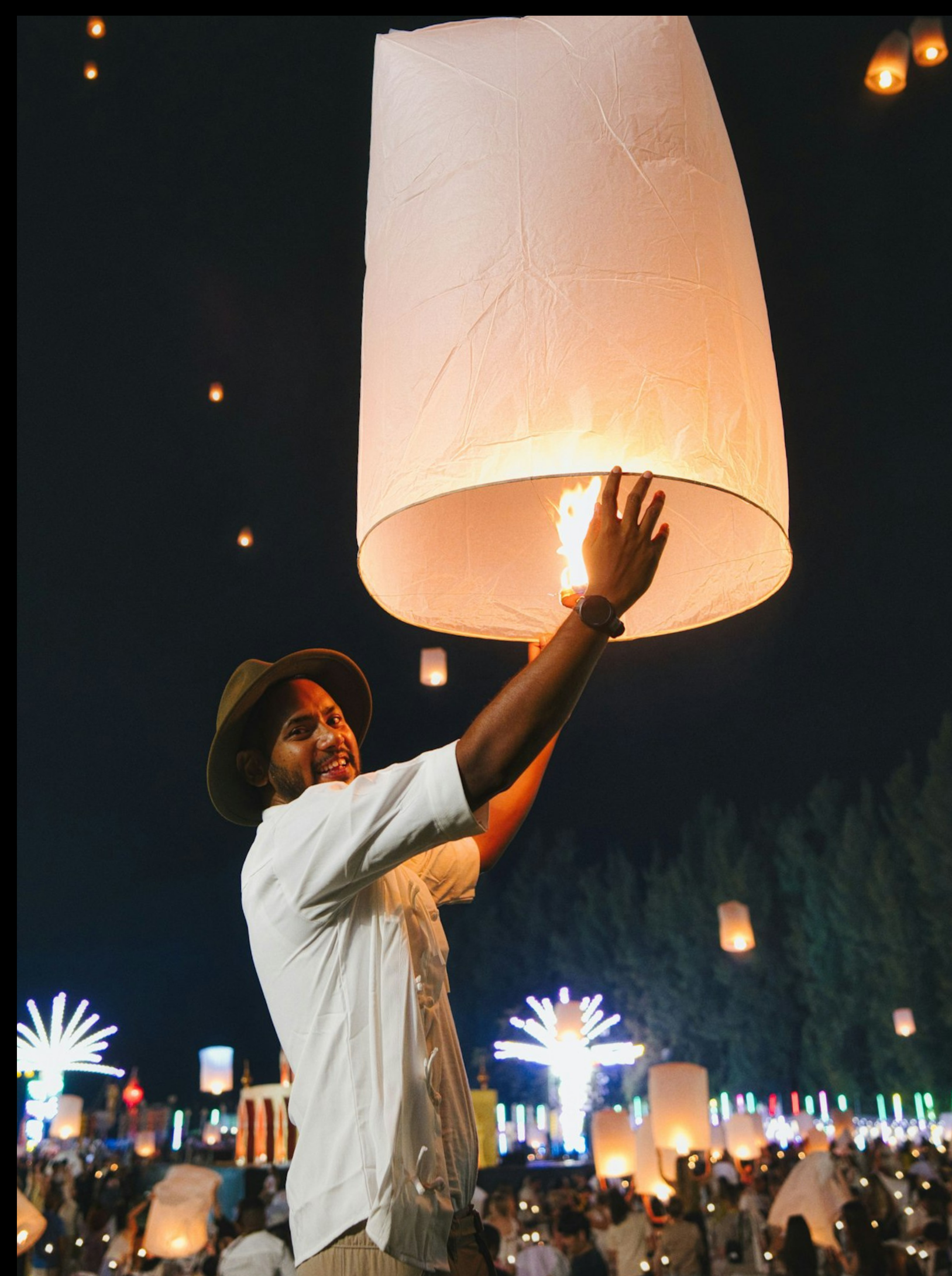 A man releasing a Yi Peng sky lantern into the night sky in Chiang Mai, Thailand