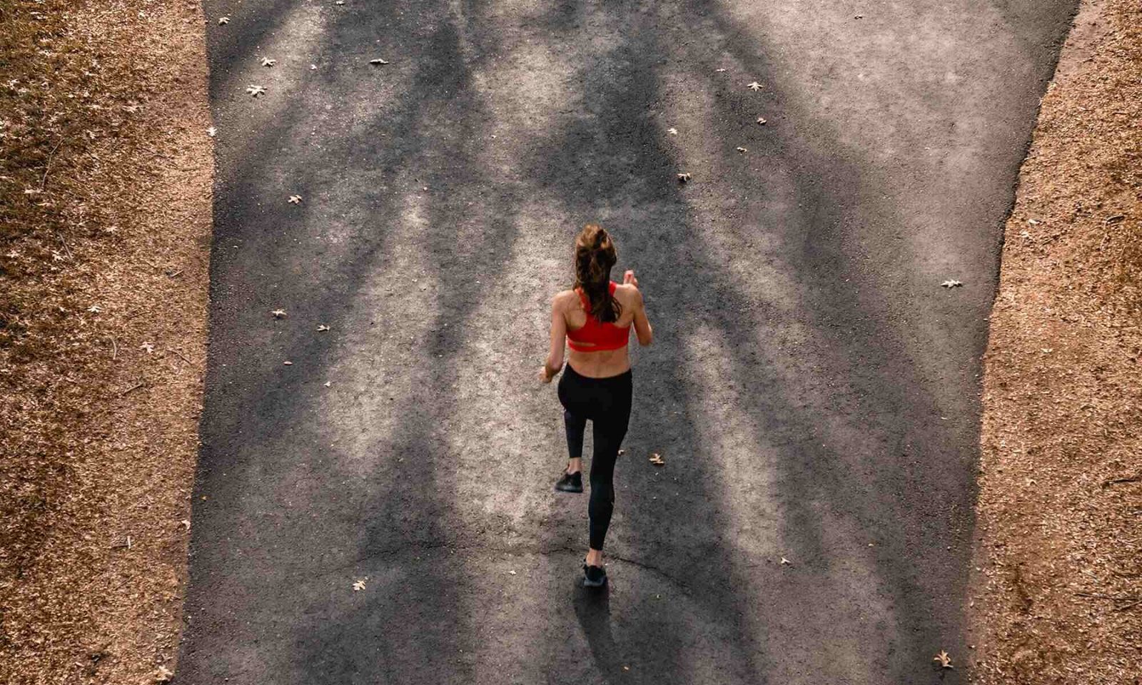 A top-down picture of a woman jogging through a park.