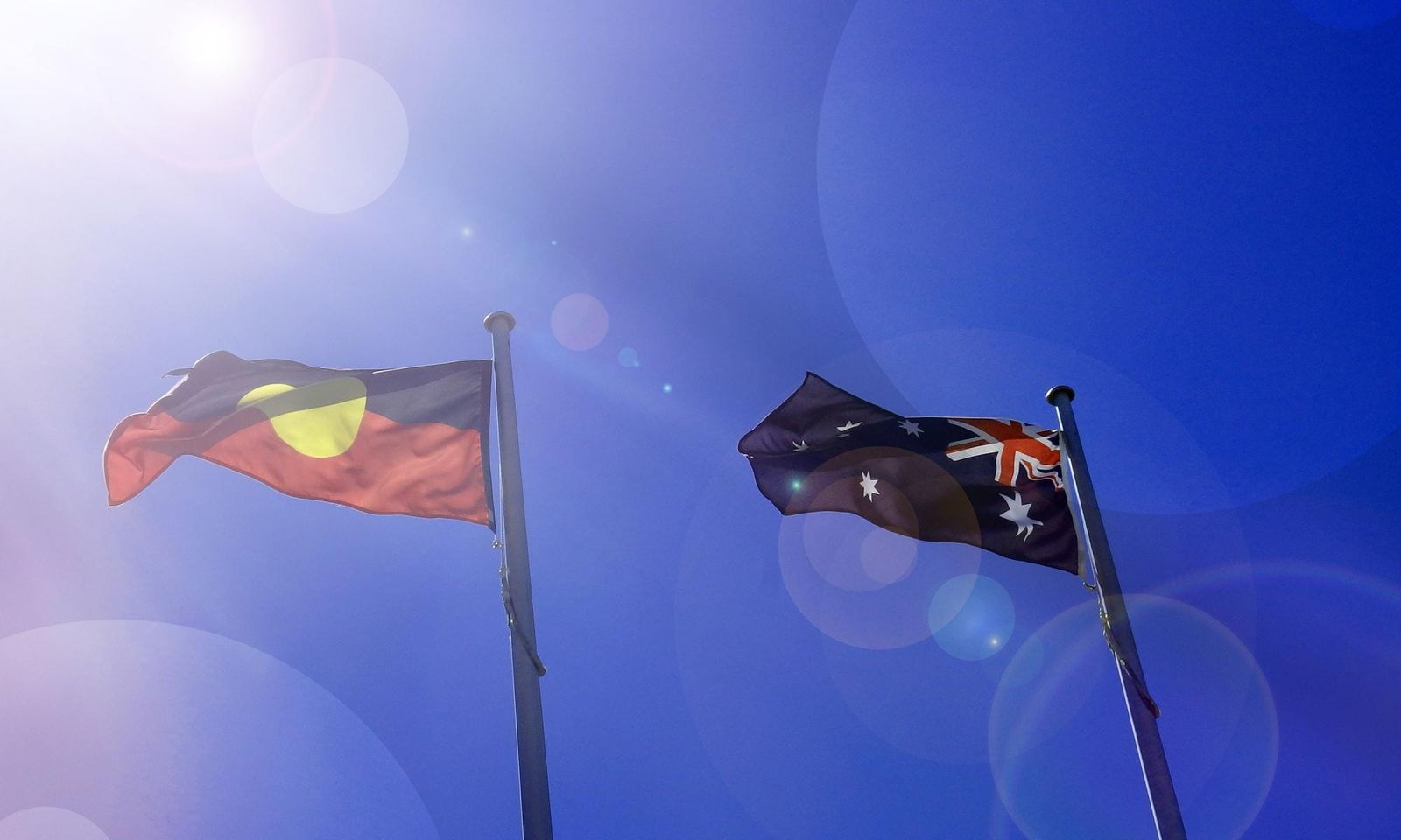 A photo of an Australian flag and an Australian Aboriginal flag.