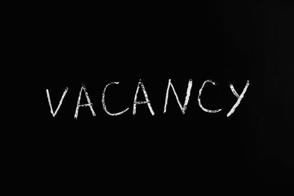 Black sign with white handwritten lettering reading "VACANCY"