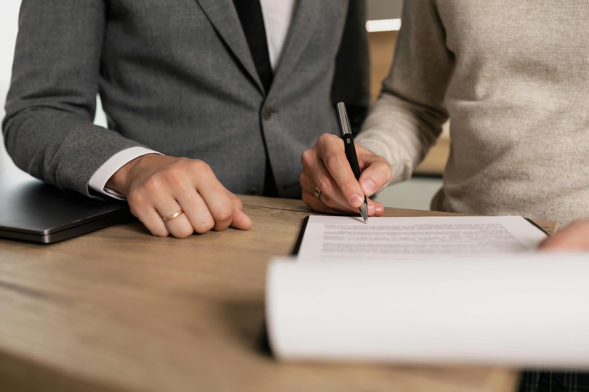 Photo of a person signing a sheet of paper.