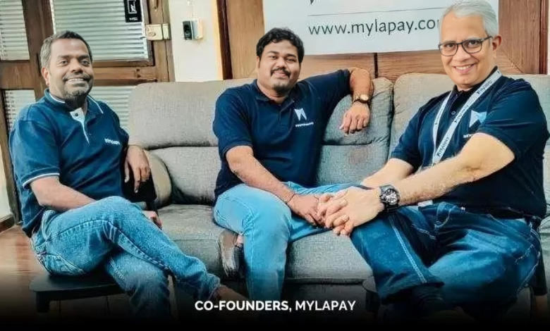 Three Mylapay co-founders sit on a grey office sofa, with Mylapay branding in the background