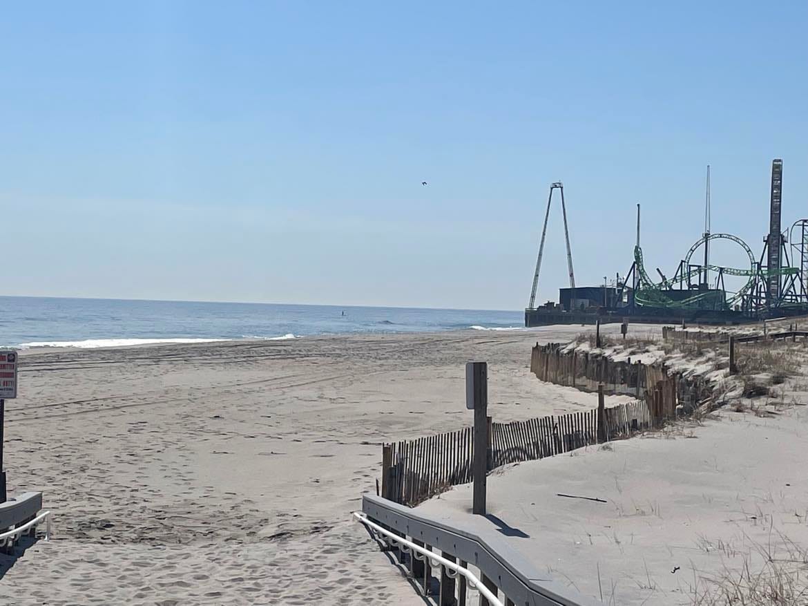 Sunny day, beach next to the Atlantic Ocean, amusement park ride in the background unused