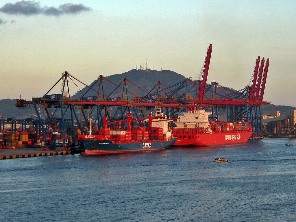 Navios de carga atracados no Porto de Santos com guindastes ao fundo