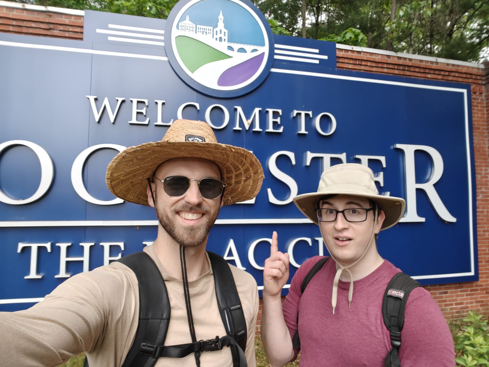 Selfie of the narrator and friend Alec smiling in front of Welcome to Rochester sign.