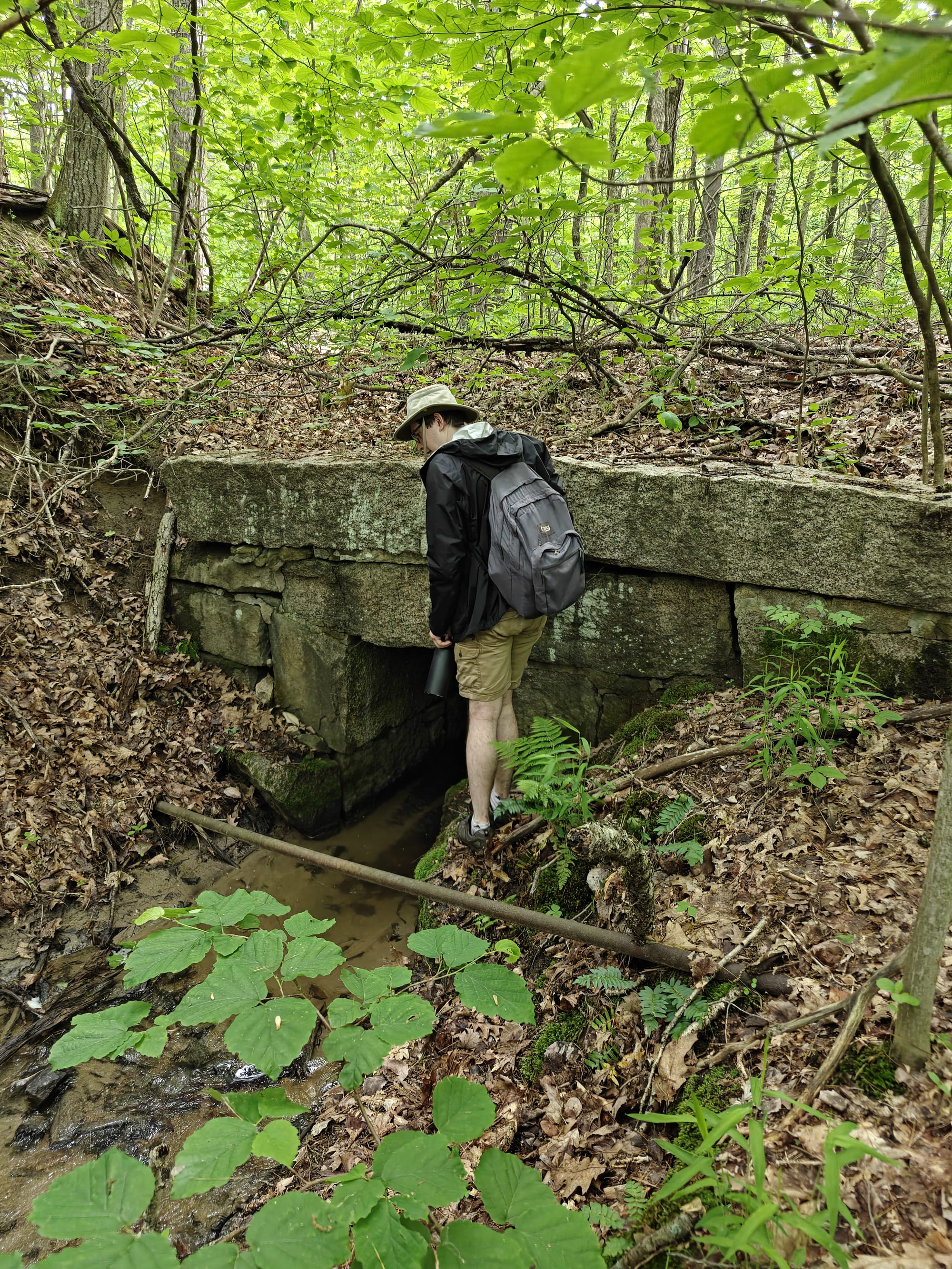Alec stands by a stone railroad culvert over a stream, exploring the defunct B&M Cocheco Line.