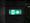 Illuminated green emergency-exit sign on a dark stone wall.