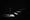 A person stands at the foot of a dark staircase; light hits the bottom and top steps but not the middle.