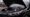 Image of a black car with an open hood showing an engine that is emitting smoke.