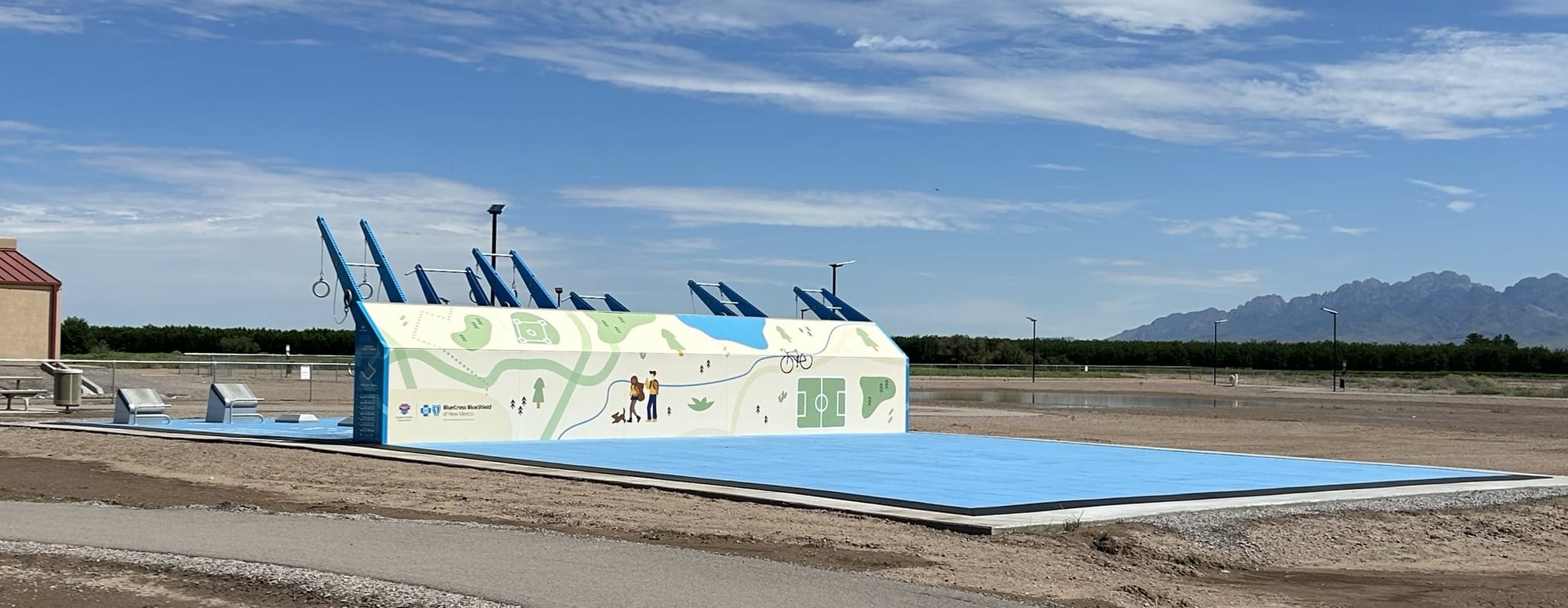 Outdoor Fitness Court Studio in La Mesa, New Mexico, with blue flooring, workout stations and exercise equipment under a partly cloudy sky.