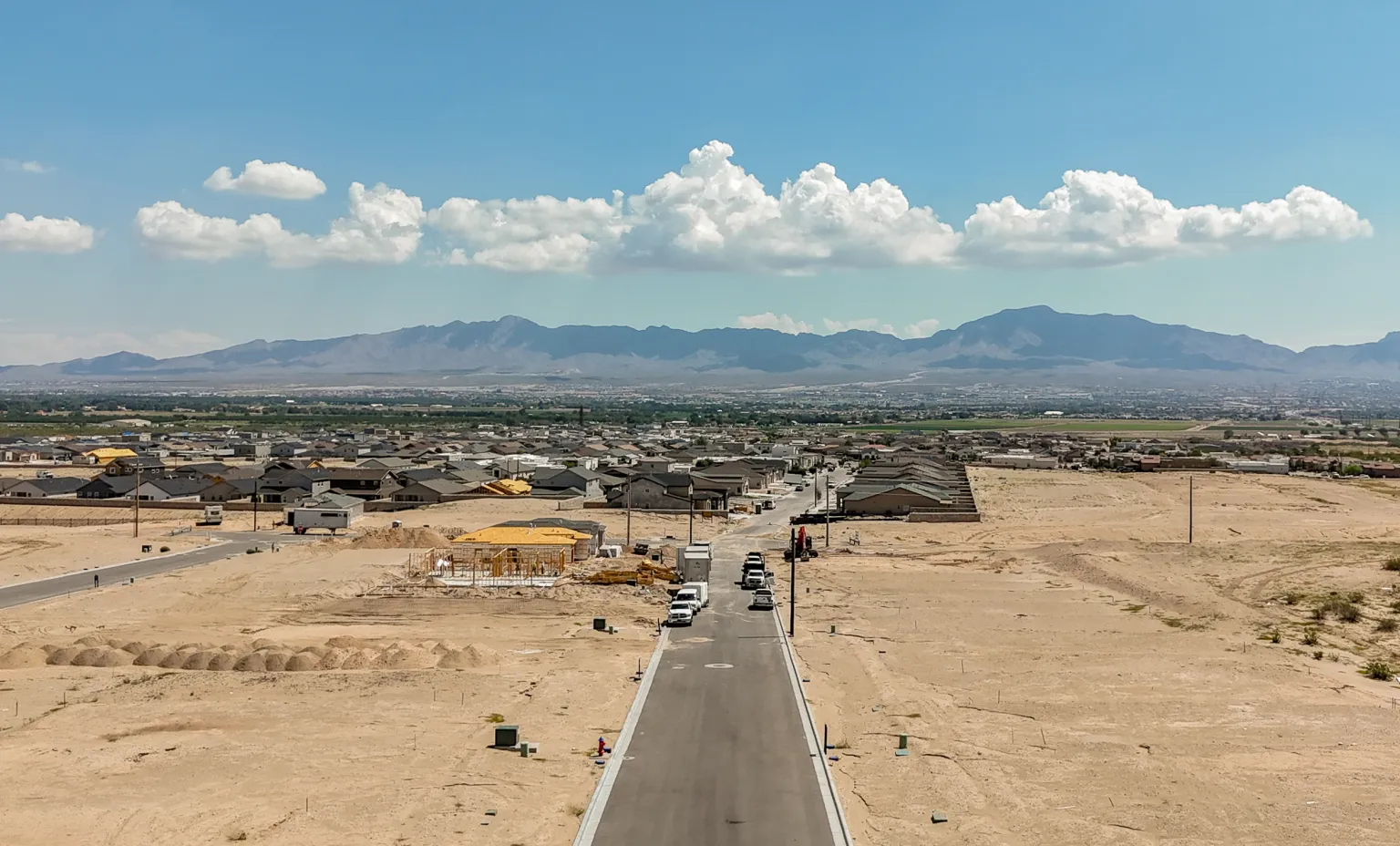 A new housing development takes shape on the desert edge near Las Cruces, with streets, homes under construction and the Organ Mountains in the distance.