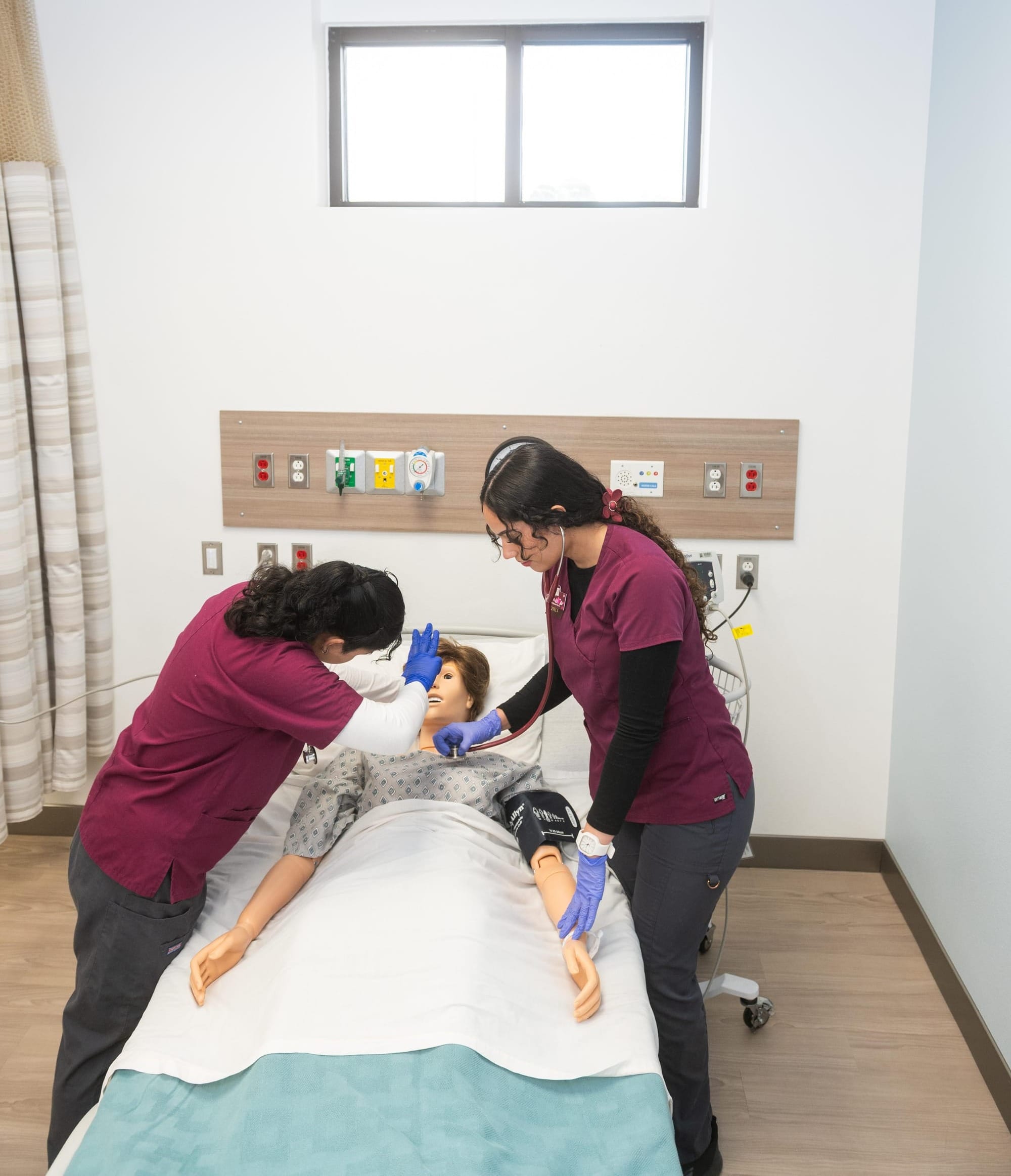 Two New Mexico State University nursing students practice patient assessment on a high-fidelity adult simulator in the renovated School of Nursing Skills and Simulation Center.