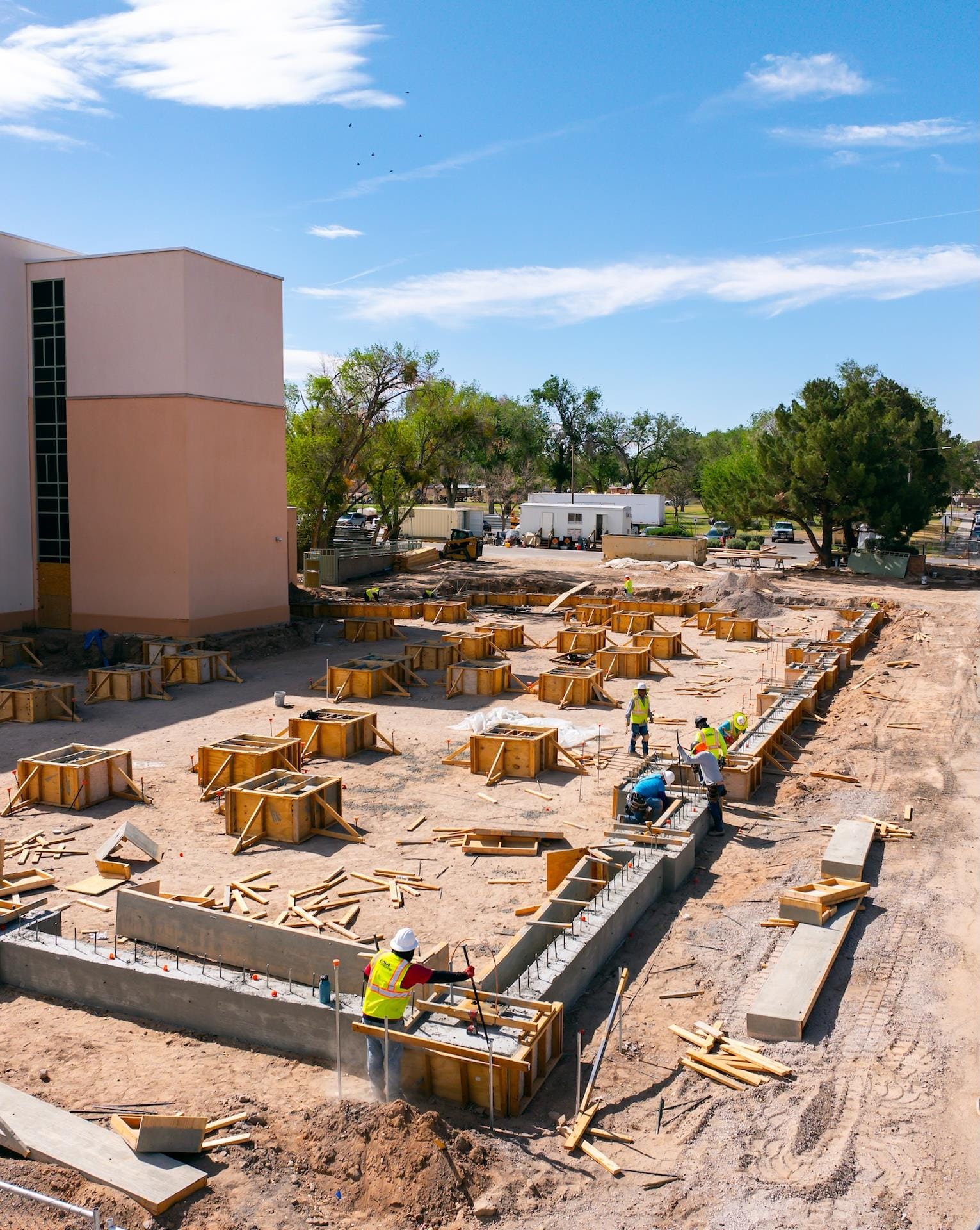 Construction workers pouring cement outside of a building.