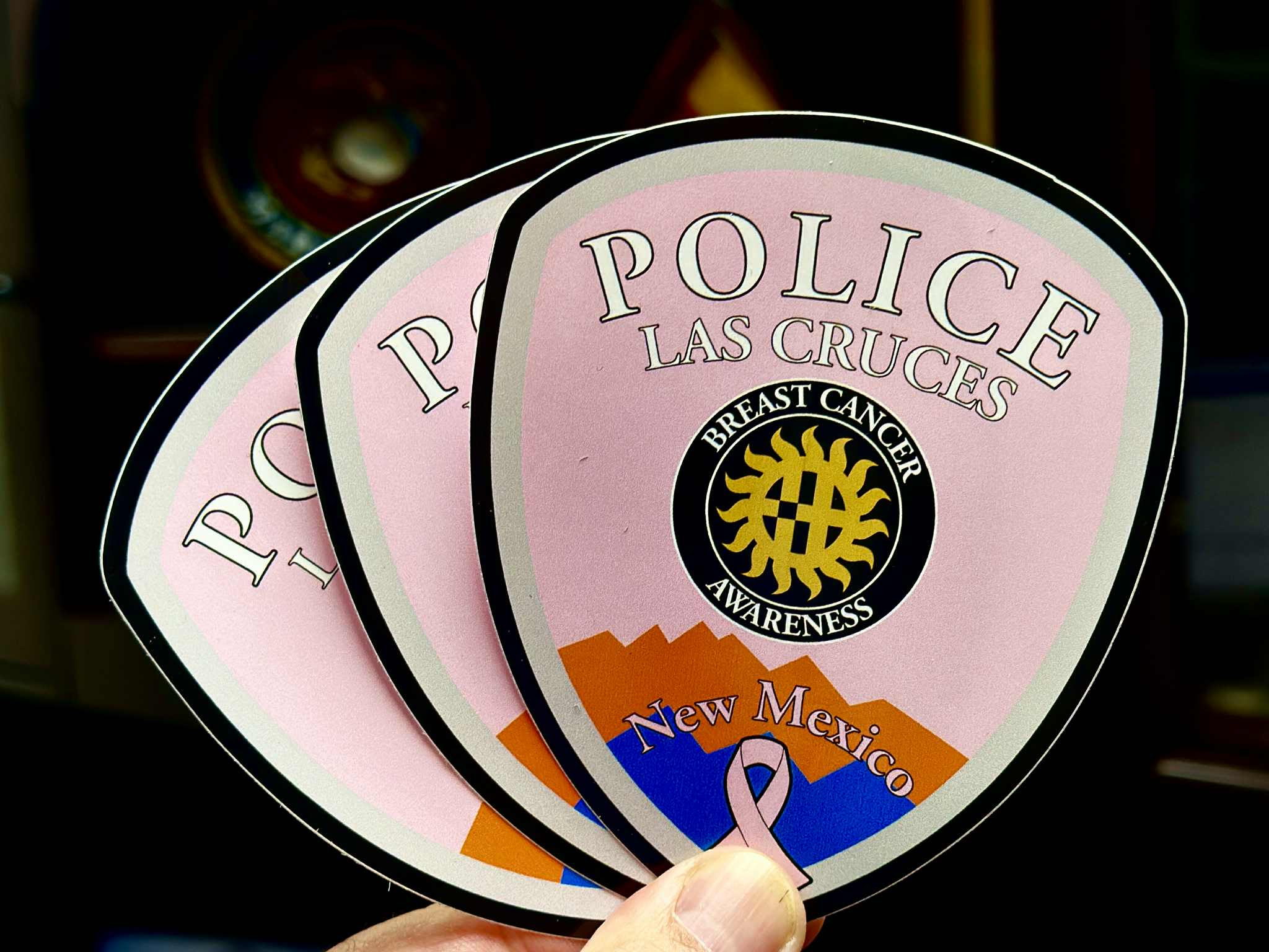 Three pink Las Cruces Police Department window decals promoting Breast Cancer Awareness, each showing the badge logo with a gold sun, mountains and a pink ribbon.