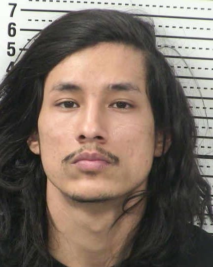 A booking photo of Dion Lee Torres, who is facing a federal firearms charge, shown against a height chart background.