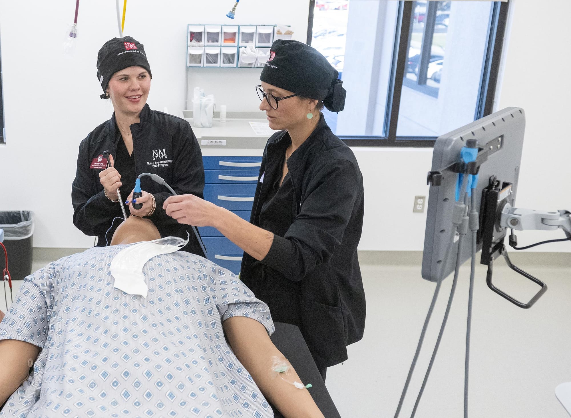 Two NMSU nurse anesthesia students practice airway management on a medical training mannequin inside the university’s new simulated operating room.