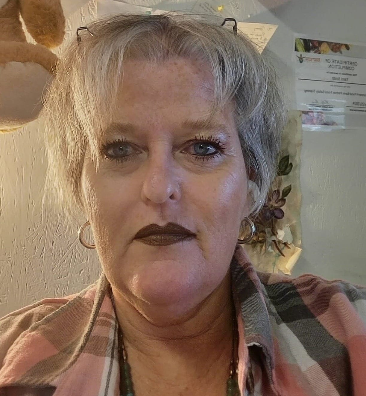 Volunteer Tami Smith looks into the camera while sitting indoors, with papers and wall decorations visible behind her.
