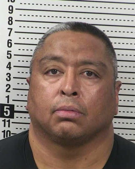 Booking photo of Felipe Hernandez, a former Las Cruces Police Department officer, shown in a front-facing head-and-shoulders view against a height chart background.
