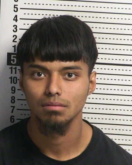 Booking photo of Tomas Rivas, a young man with short dark hair and a trimmed goatee, standing in front of a height chart background.