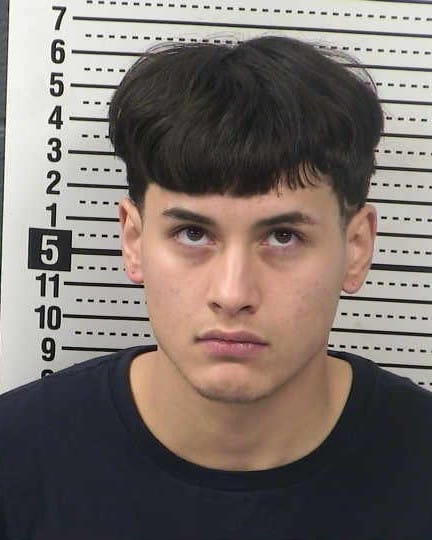 Booking photo of Carlos Hernandez against a height chart background