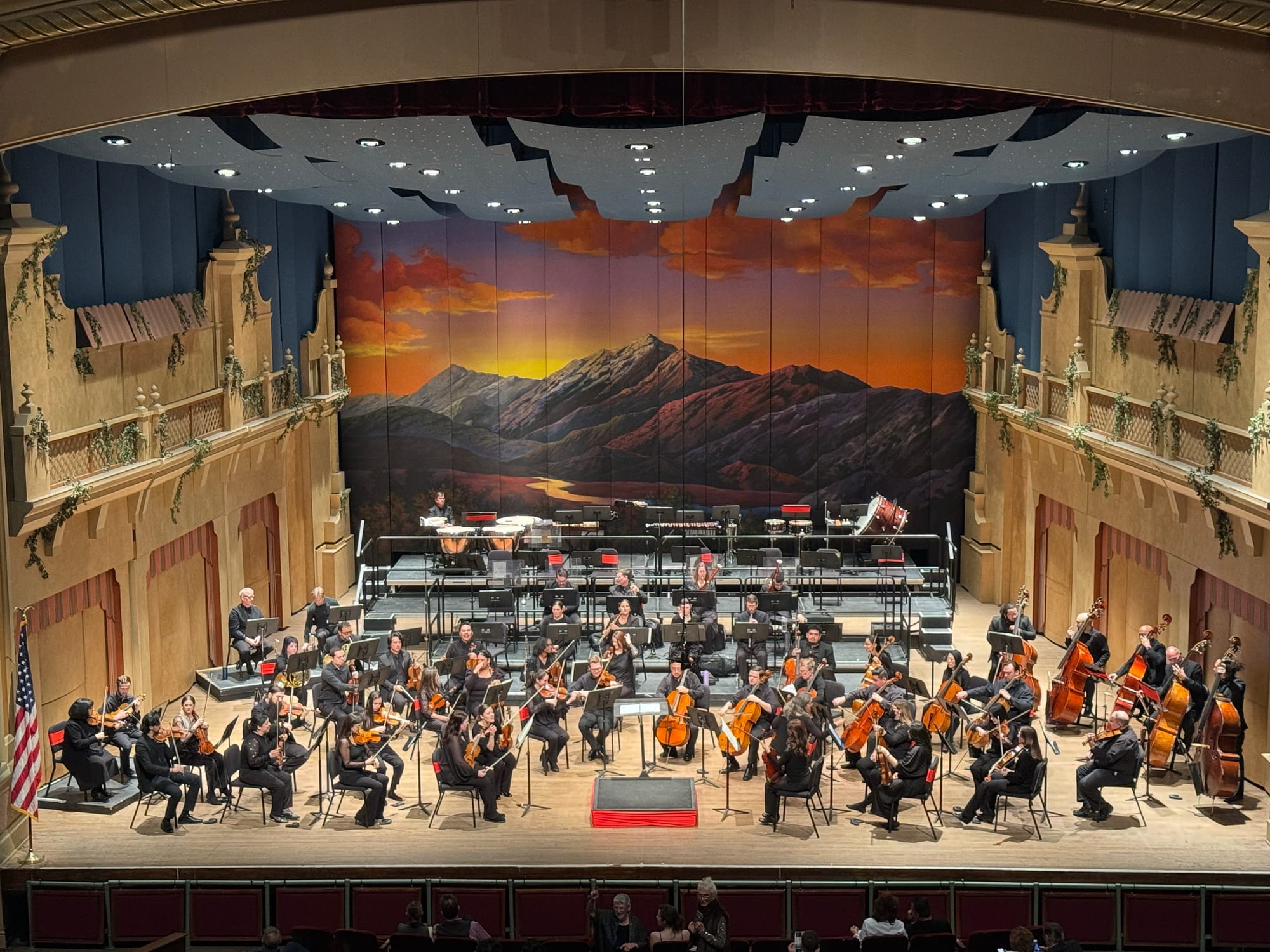 The El Paso Symphony Orchestra performs onstage beneath a painted mountain sunset backdrop during “The Seventh Symphonies: Classical Poetry” concert.