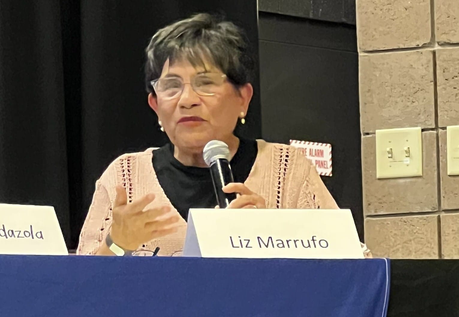 Liz Marrufo speaks into a microphone during a RECA forum at Doña Ana Community College in Las Cruces.