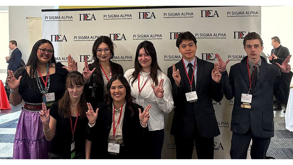 Group of NMSU political science students at Pi Sigma Alpha conference backdrop, representing research presentations