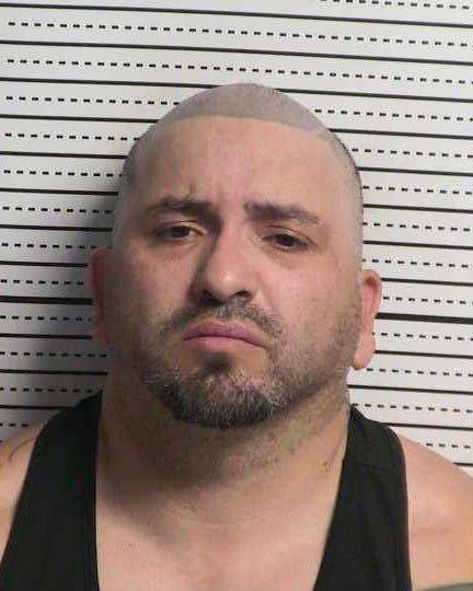 Booking photo of Billy J. Porter, facing forward against a height chart background, with a shaved head and trimmed goatee, wearing a black tank top and a neutral expression.