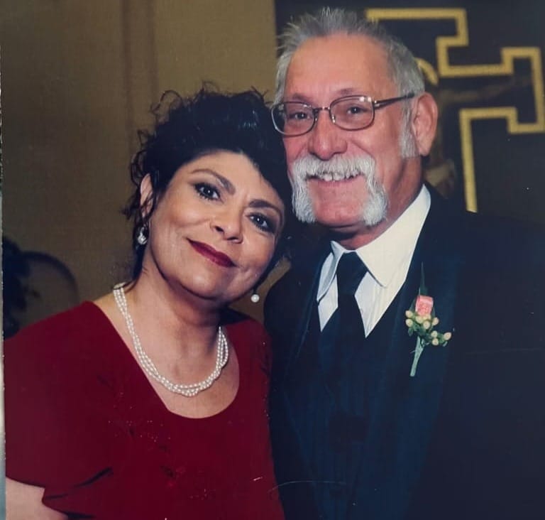 Christine and Sal Telles pose together in formal attire for a portrait photo.