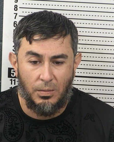 Booking photo of Enrique S. Enriquez in front of a height chart background.