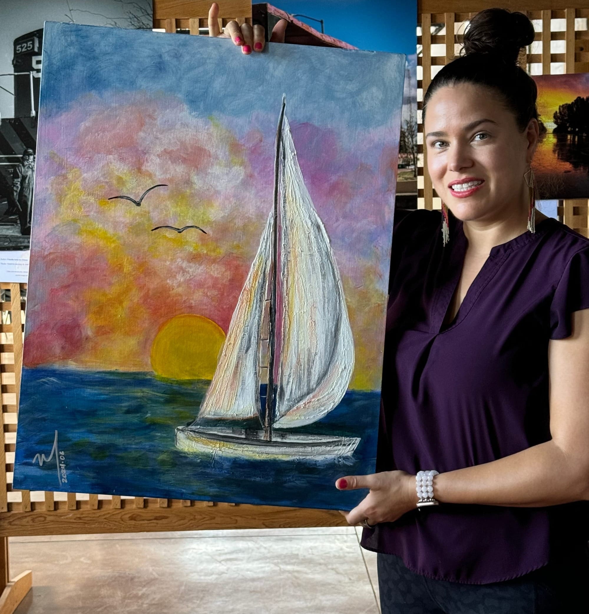 Monica LeBaron holding a painting of a boat.