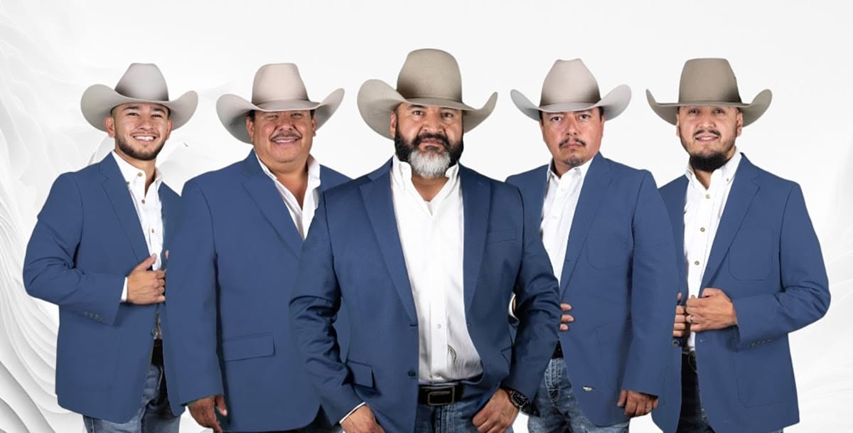Five members of Cautivo Norteño wearing blue blazers and cowboy hats pose together in a studio portrait.