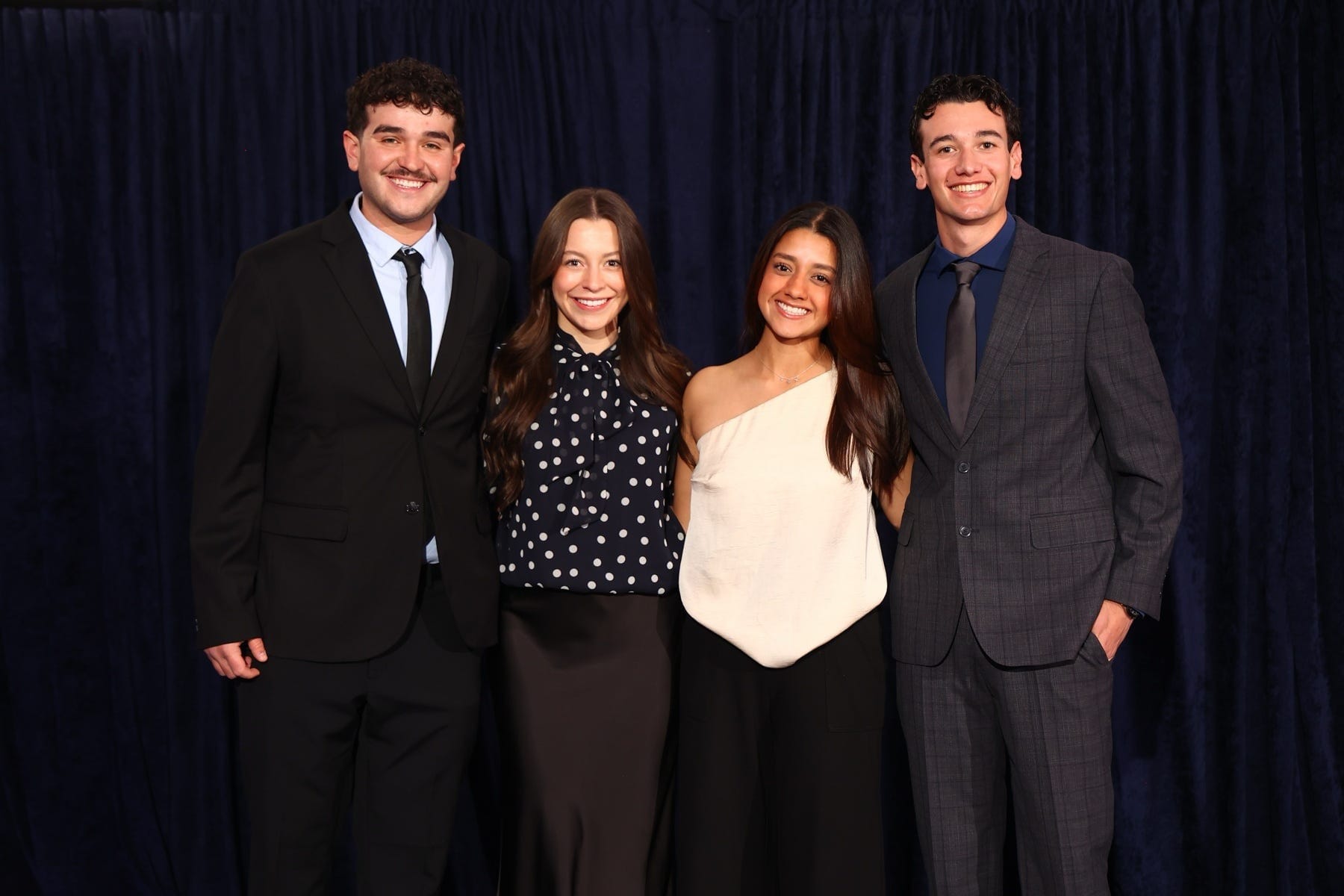 Four New Mexico State University business students pose together in formal attire after competing at a national ethics case competition.