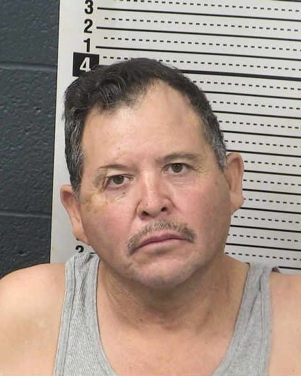 Booking photo of Pedro Duran Bustillos against a height chart background.