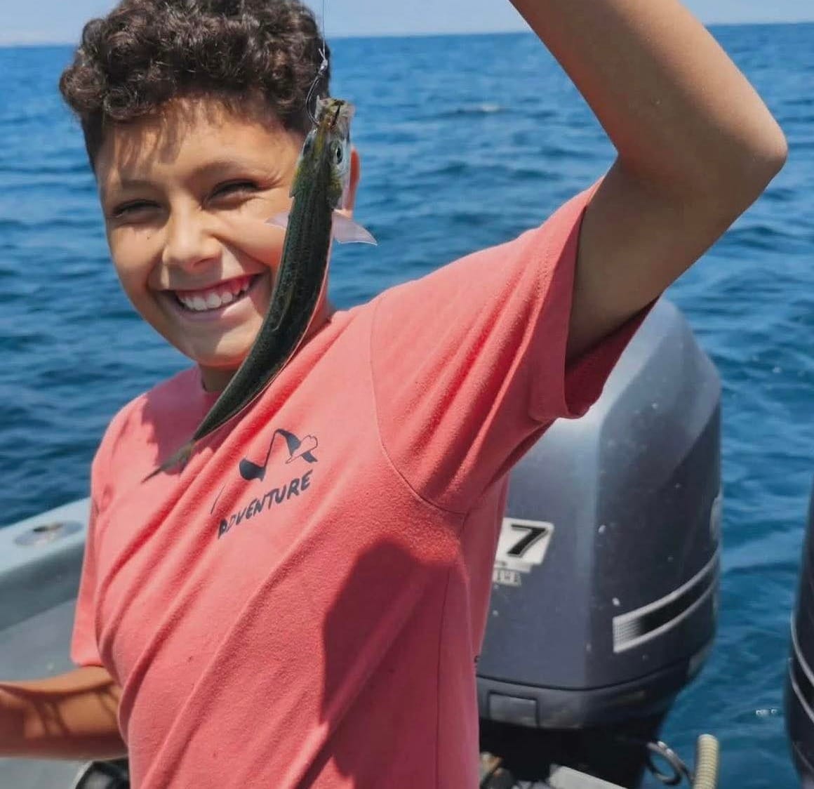 Undated photo of Chris holding a fish on a boat with open water in the background.