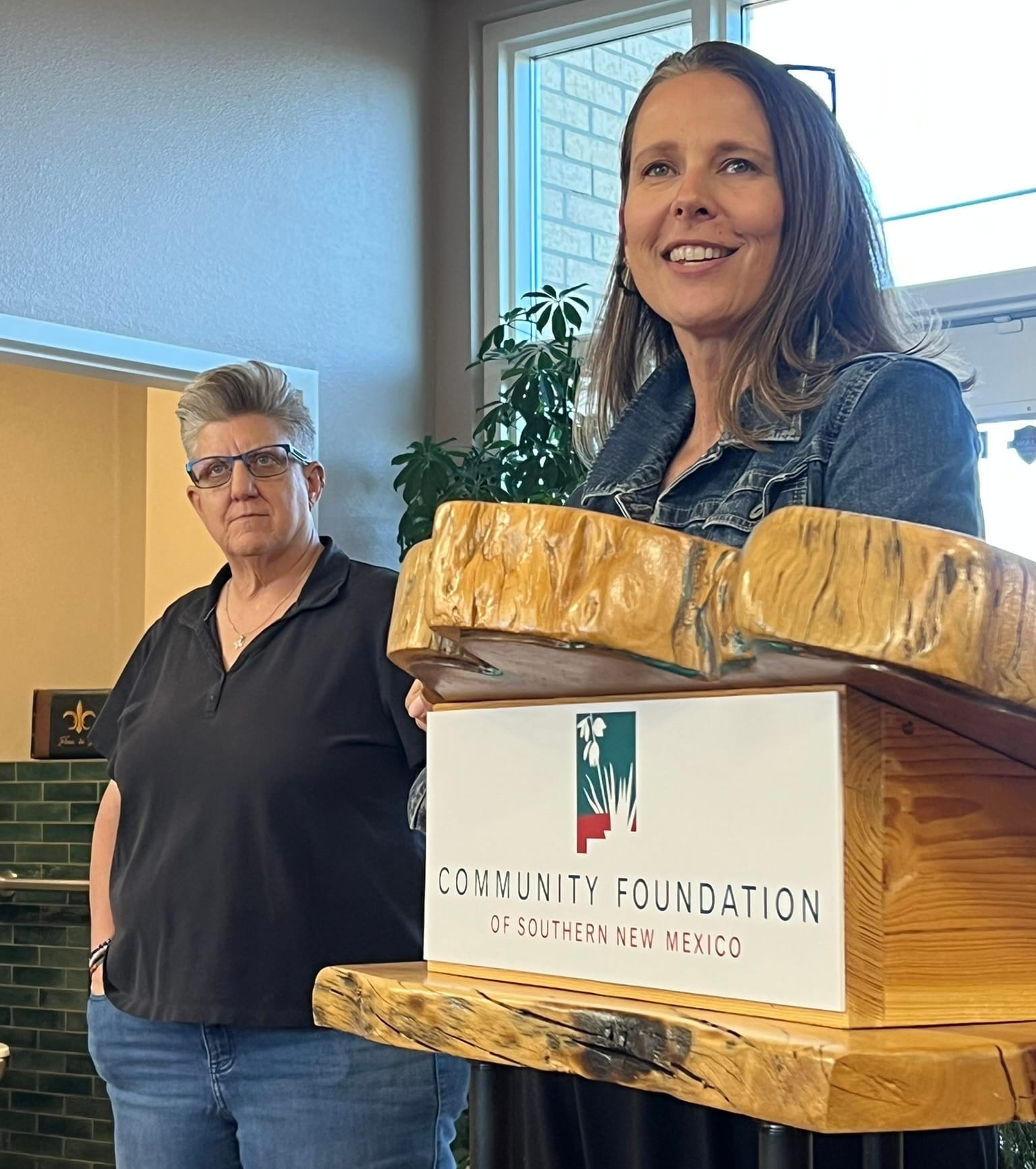 Terra Winter speaks at a podium during a Southern New Mexico Giving Day presentation as Carrie Hamblen looks on at a Las Cruces event.