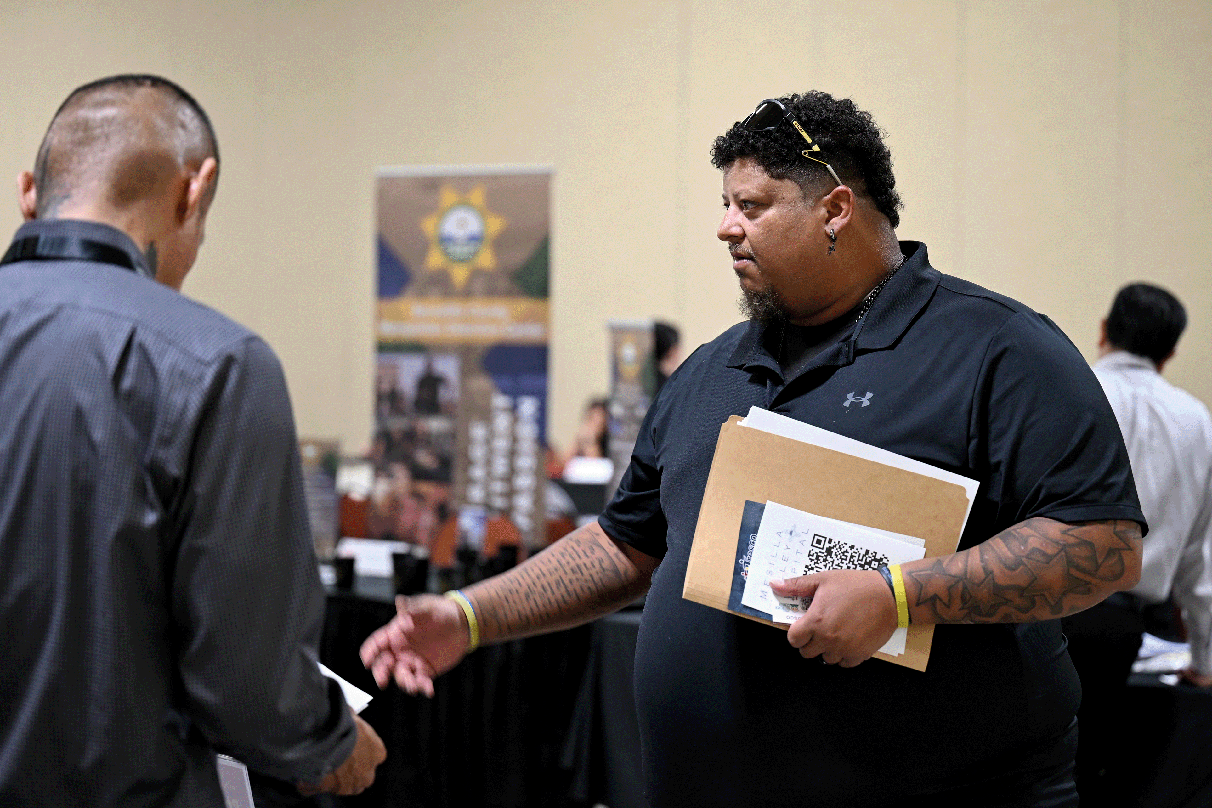 Brent Jones, a U.S. Army veteran, speaks with a representative while holding documents at the Heroes Hiring Heroes event in Las Cruces.