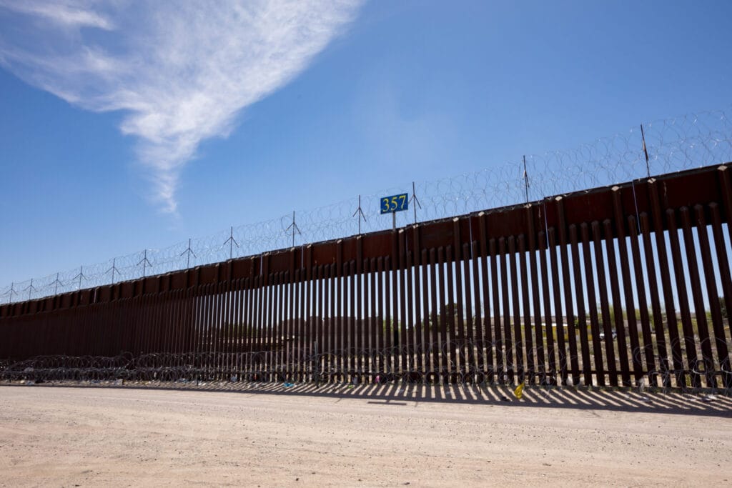 A section of the U.S.-Mexico border wall topped with razor wire stretches across the desert landscape near Sunland Park.