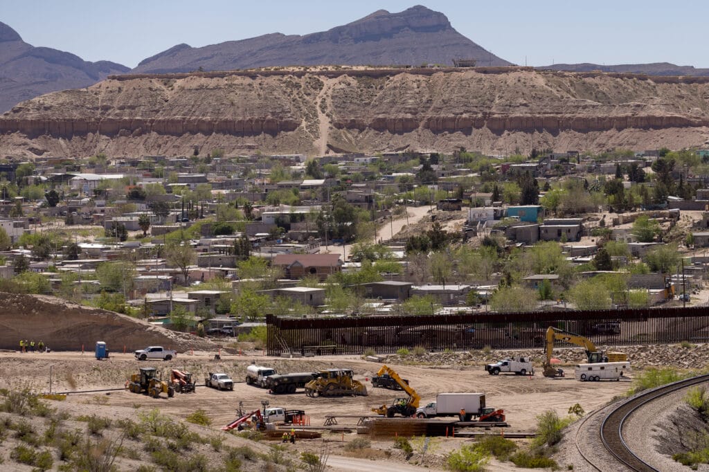 Construction equipment and crews work along the U.S.-Mexico border wall near a residential area in Sunland Park.