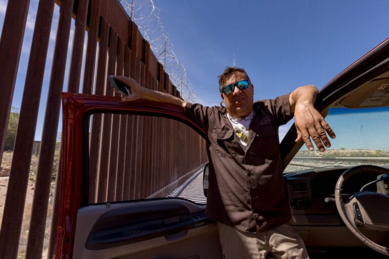Robert Ardovino stands beside his vehicle along the U.S.-Mexico border wall near Sunland Park as construction continues nearby.