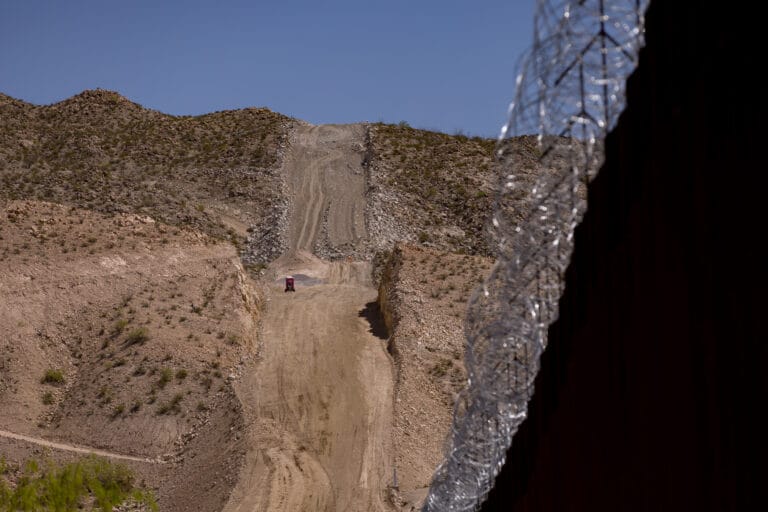 A graded path cuts through the hillside at Mount Cristo Rey near the U.S.-Mexico border wall, where construction work is underway.