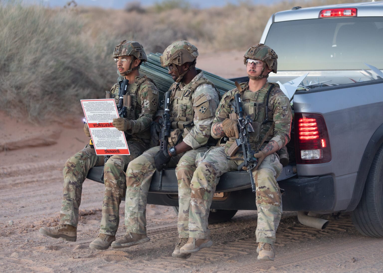 U.S. soldiers sit on the back of a truck holding a warning sign marking the boundary of a militarized border zone in southern New Mexico.