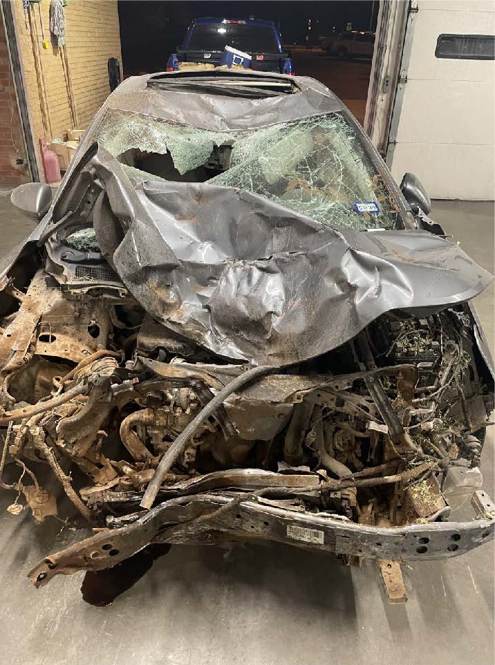 Severely damaged car with crushed front end and shattered windshield following a high-speed crash.