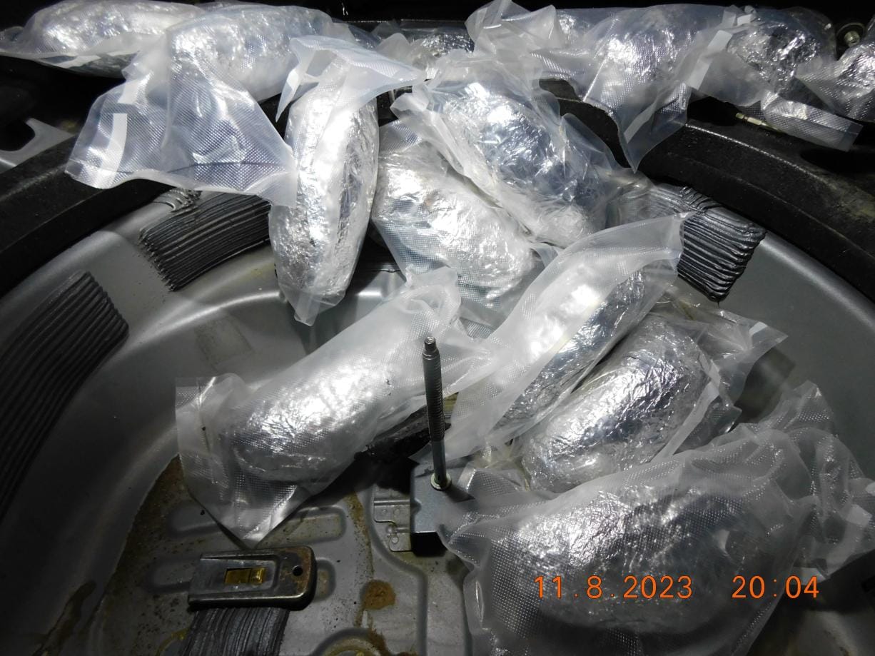 Multiple vacuum-sealed packages of methamphetamine wrapped in plastic inside a vehicle trunk.
